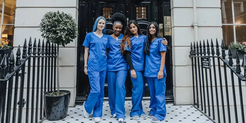 Four nurses in blue scrubs outside a Georgian clinic entrance at our Harley Street clinic, Ultherapy skin lifting London